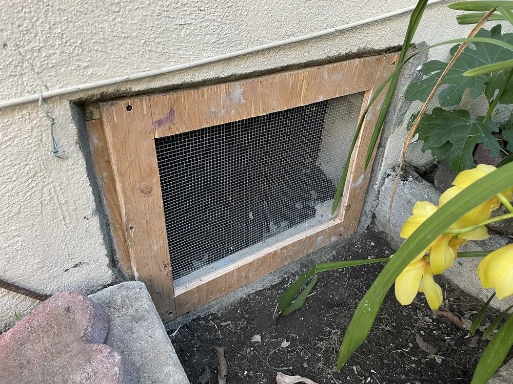 Crawlspace vent rebuilt with a wood frame and metal screening on an older Long Beach home